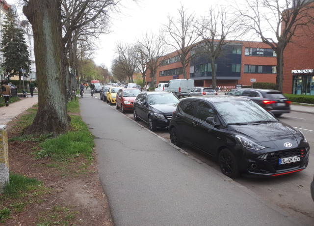 Ein Bild der Falkenstraße und des Radweg, mit Autos welche eine Spur zuparken.